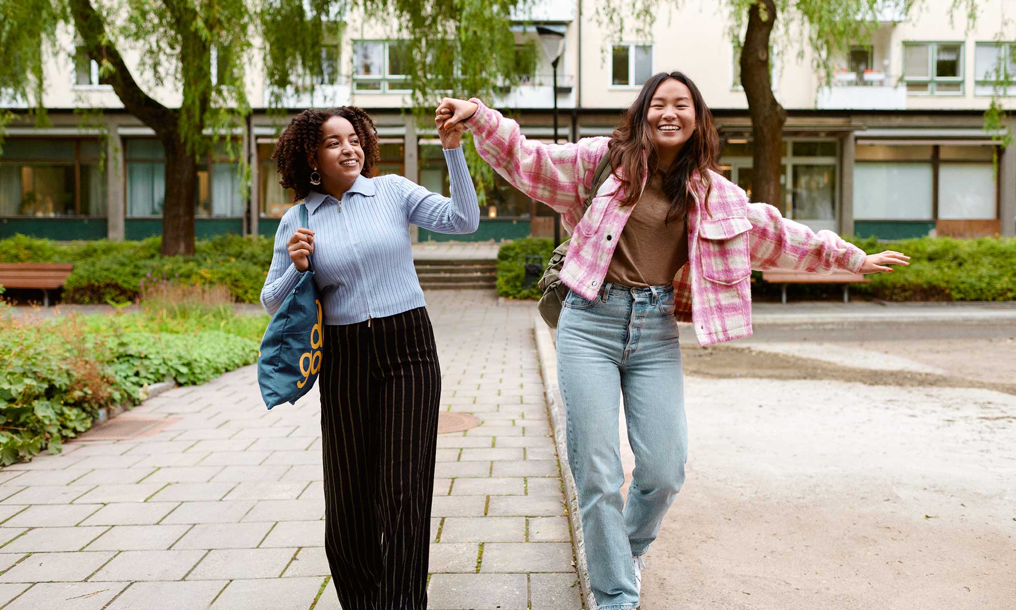 Two young women in a balancing act on the edge of a pavement